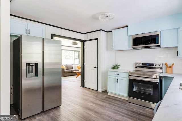 2343 Dawn Dr, Decatur, GA 30032 - kitchen featuring stainless steel appliances, wood finished floors, backsplash, crown molding, and light stone countertops