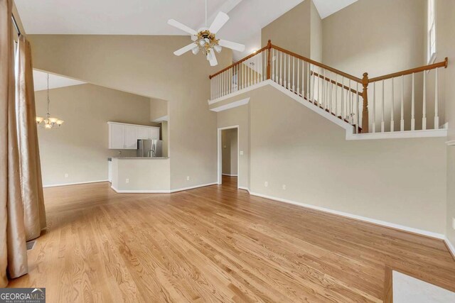 4815 Rapids Cir NW, Acworth, GA 30102 - unfurnished living room with light wood-type flooring, a ceiling fan, high vaulted ceiling, and a chandelier