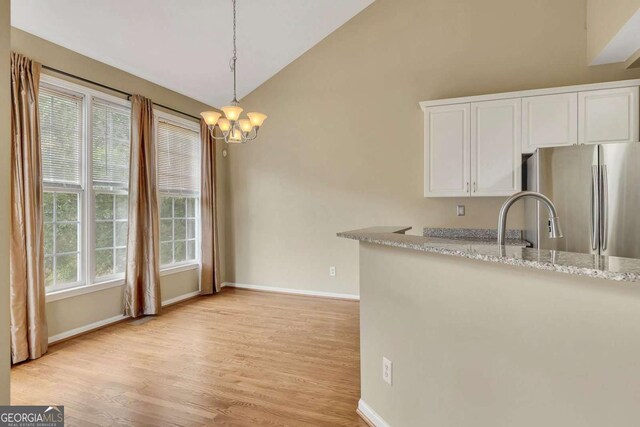4815 Rapids Cir NW, Acworth, GA 30102 - kitchen with freestanding refrigerator, white cabinetry, lofted ceiling, light wood finished floors, and light stone countertops