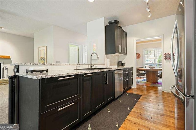 2004 Spicers Ln, Woodstock, GA 30189 - kitchen with stainless steel appliances, a sink, light wood-type flooring, dark cabinets, and a peninsula