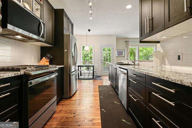 2004 Spicers Ln, Woodstock, GA 30189 - kitchen featuring appliances with stainless steel finishes, a sink, light wood-type flooring, decorative backsplash, and light stone counters