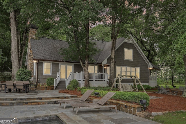 3612 Bill Gardner Pkwy, Locust Grove, GA 30248 - view of front of house featuring a shingled roof, a patio area, an outdoor fire pit, and a chimney