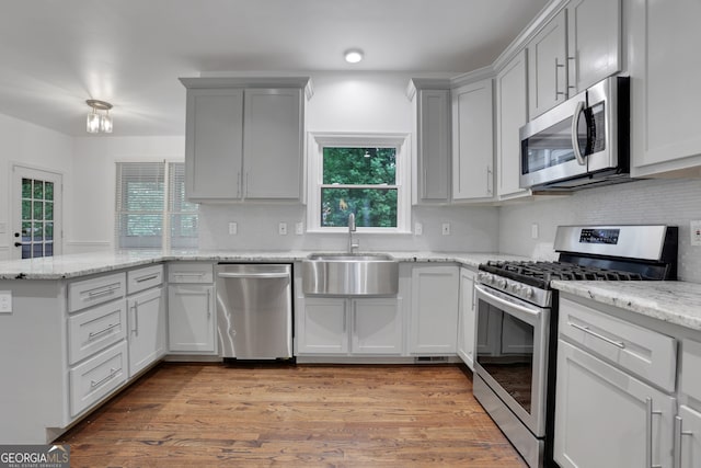 11280 Brookhollow Trl, Alpharetta, GA 30022 - kitchen with appliances with stainless steel finishes, a peninsula, decorative backsplash, light wood-style floors, and light stone countertops