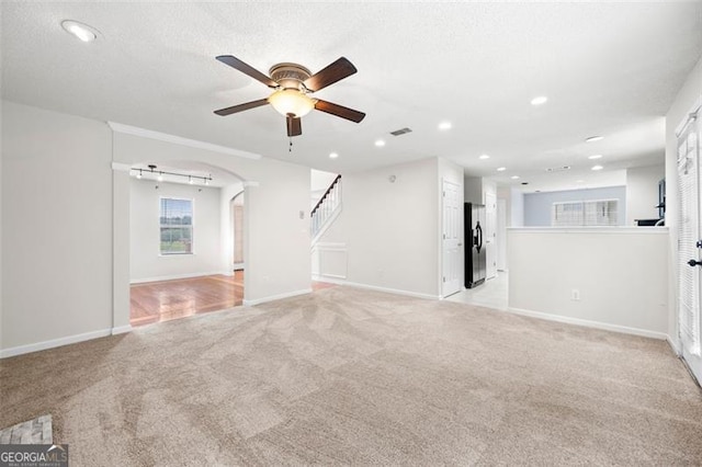 1486 Rogers Crossing Dr, Lithonia, GA 30058 - unfurnished living room featuring a ceiling fan, light carpet, arched walkways, recessed lighting, and stairway
