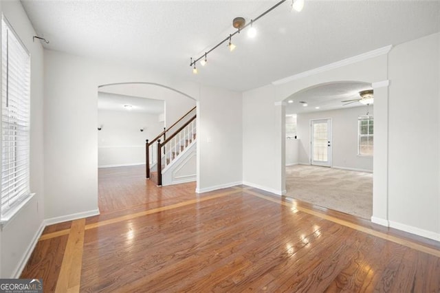 1486 Rogers Crossing Dr, Lithonia, GA 30058 - empty room with arched walkways, ceiling fan, wood finished floors, stairs, and rail lighting