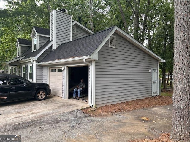 4514 Tifton Ct, Powder Springs, GA 30127 - view of property exterior with an attached garage, a chimney, roof with shingles, driveway, and view of wooded area