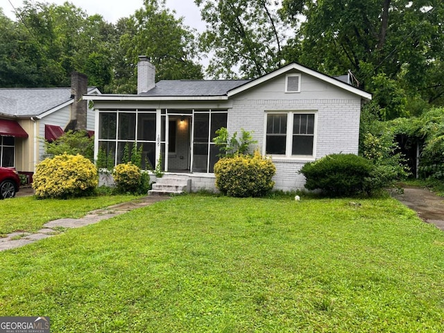 1829 Mercer Ave, College Park, GA 30337 - view of front of house featuring brick siding, a front yard, a sunroom, and a chimney
