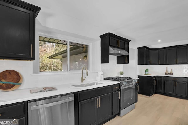 696 Kenilworth Cir, Stone Mountain, GA 30083 - kitchen with appliances with stainless steel finishes, a sink, dark cabinetry, tasteful backsplash, and light stone counters