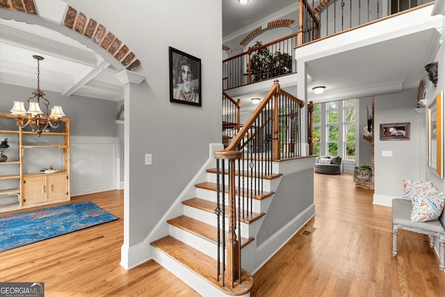 979 Pathview Ct, Dacula, GA 30019 - stairs featuring crown molding, wood finished floors, a chandelier, beam ceiling, and coffered ceiling