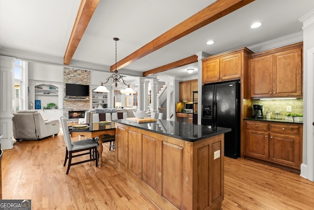 979 Pathview Ct, Dacula, GA 30019 - kitchen featuring black refrigerator with ice dispenser, decorative columns, a kitchen island, a stone fireplace, and ornamental molding