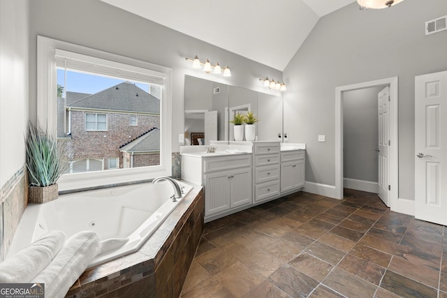 979 Pathview Ct, Dacula, GA 30019 - bathroom featuring double vanity, a whirlpool tub, stone tile flooring, baseboards, and high vaulted ceiling