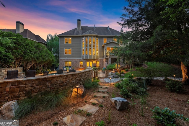 979 Pathview Ct, Dacula, GA 30019 - back of house at dusk with a patio area, a chimney, and stairway