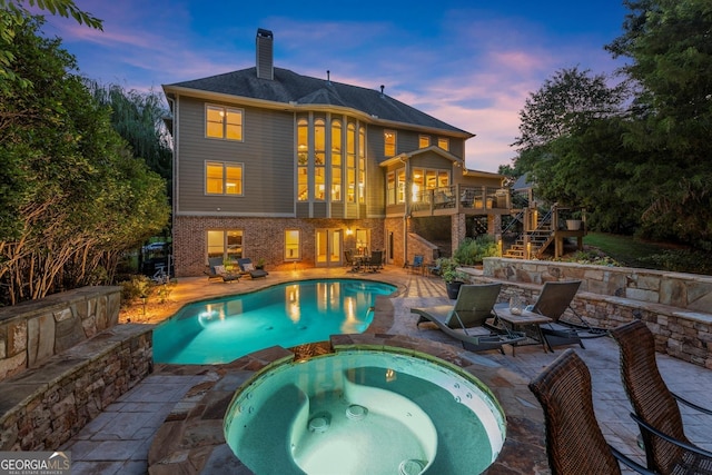 979 Pathview Ct, Dacula, GA 30019 - back of property at dusk featuring stairs, a chimney, a patio area, brick siding, and a pool with connected hot tub