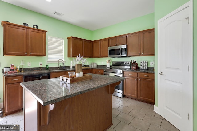 17 Sagefield Dr, Ellabell, GA 31308 - kitchen with appliances with stainless steel finishes, light tile patterned floors, a sink, a center island, and dark stone countertops