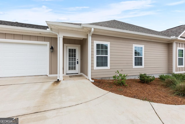 488 Nandina Ct, Warner Robins, GA 31088 - view of exterior entry with an attached garage, concrete driveway, roof with shingles, and board and batten siding