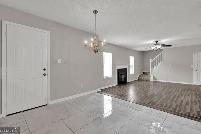 3885 Riverview Chase Blf, Ellenwood, GA 30294 - unfurnished living room featuring light marble finish floors, stairs, baseboards, a chandelier, and a glass covered fireplace