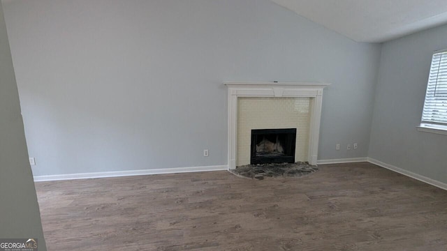 5710 Cardigan Trce, Sugar Hill, GA 30518 - unfurnished living room with wood finished floors, a fireplace with raised hearth, lofted ceiling, and baseboards