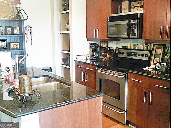 4561 Olde Perimeter Way Unit 608, Dunwoody, GA 30346 - kitchen featuring appliances with stainless steel finishes, dark stone counters, and light wood-style flooring