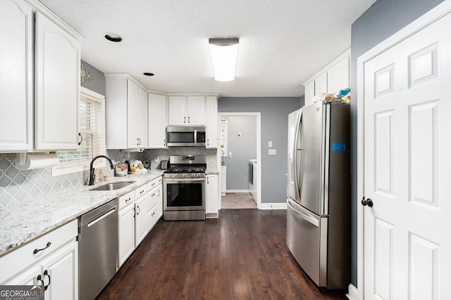 1112 Sutton Dr, Mcdonough, GA 30252 - kitchen featuring appliances with stainless steel finishes, white cabinetry, tasteful backsplash, light stone countertops, and washer / clothes dryer