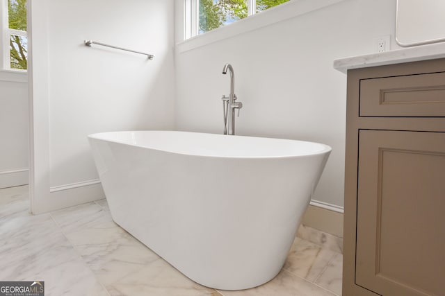 1036 Dell Ave SE, Smyrna, GA 30080 - bathroom with marble look tile flooring, a freestanding tub, baseboards, and vanity
