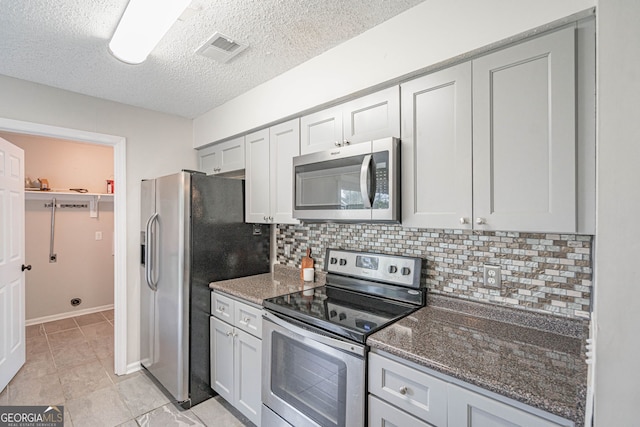 755 Madison Dr, Hinesville, GA 31313 - kitchen featuring appliances with stainless steel finishes, backsplash, dark stone counters, a textured ceiling, and baseboards