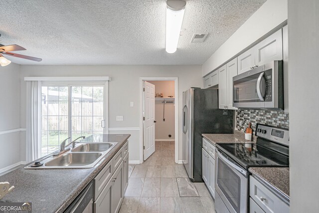755 Madison Dr, Hinesville, GA 31313 - kitchen featuring stainless steel appliances, a sink, ceiling fan, dark countertops, and tasteful backsplash
