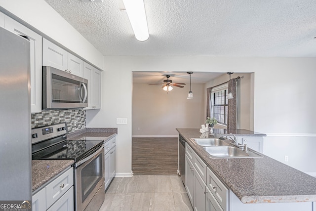 755 Madison Dr, Hinesville, GA 31313 - kitchen with appliances with stainless steel finishes, a sink, ceiling fan, an island with sink, and a textured ceiling