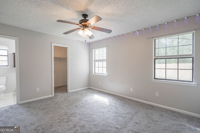 755 Madison Dr, Hinesville, GA 31313 - unfurnished bedroom with carpet floors, a walk in closet, a textured ceiling, connected bathroom, and a closet