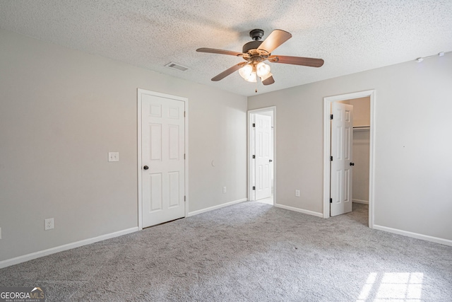 755 Madison Dr, Hinesville, GA 31313 - unfurnished bedroom with carpet flooring, a textured ceiling, baseboards, ceiling fan, and a walk in closet