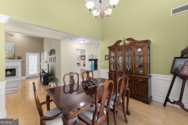 92 Isaiah Dr, Jefferson, GA 30549 - dining area featuring a chandelier, a towering ceiling, a lit fireplace, light wood-style flooring, and ornamental molding