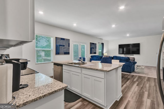 289 Pond Ct, Hoschton, GA 30548 - kitchen with stainless steel dishwasher, dark wood-style floors, white cabinetry, a kitchen island with sink, and light stone countertops