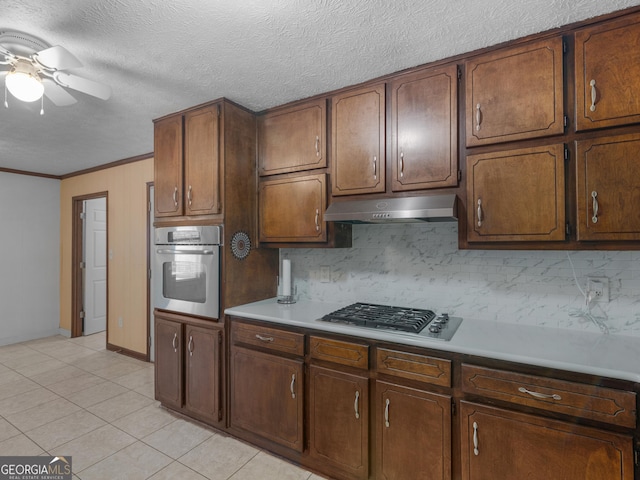 1001 Stagecoach Rd, Stockbridge, GA 30281 - kitchen with appliances with stainless steel finishes, under cabinet range hood, tasteful backsplash, a ceiling fan, and ornamental molding