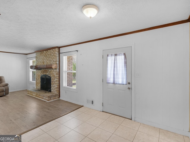 1001 Stagecoach Rd, Stockbridge, GA 30281 - entrance foyer featuring ornamental molding, a textured ceiling, a fireplace, baseboards, and light wood-style floors