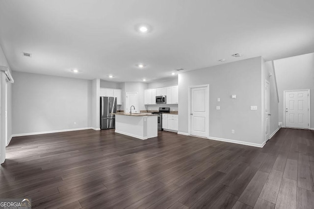 1998 Nuthatch Dr, Hoschton, GA 30548 - unfurnished living room featuring baseboards, recessed lighting, dark wood finished floors, and a sink