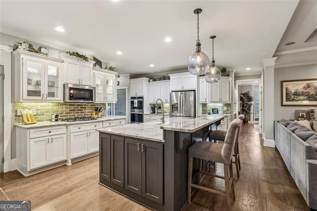3665 Pennington Rd, Cumming, GA 30041 - kitchen featuring stainless steel appliances, crown molding, decorative backsplash, white cabinetry, and a breakfast bar