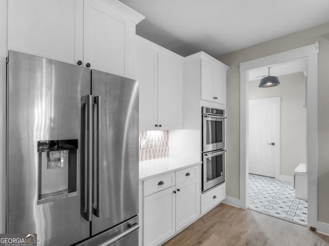 319 S Mount Carmel Rd, Mcdonough, GA 30253 - kitchen with appliances with stainless steel finishes, light countertops, white cabinets, light wood-style flooring, and baseboards