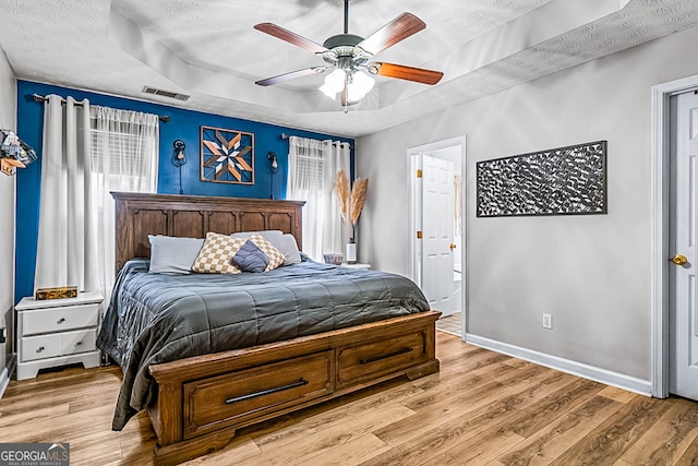 161 Mills Dr, Covington, GA 30016 - bedroom featuring light wood-style flooring, baseboards, a raised ceiling, ceiling fan, and a textured ceiling
