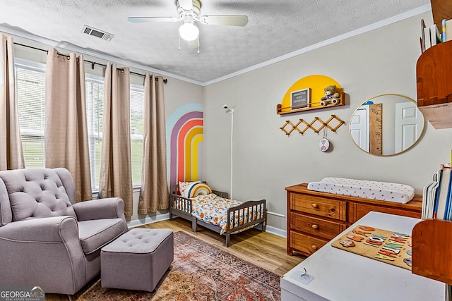 161 Mills Dr, Covington, GA 30016 - bedroom with wood finished floors, a nursery area, a textured ceiling, baseboards, and ornamental molding