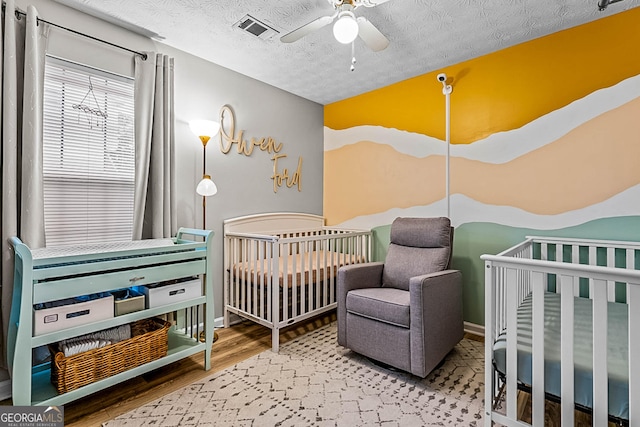 161 Mills Dr, Covington, GA 30016 - bedroom featuring wood finished floors, a textured ceiling, and a ceiling fan