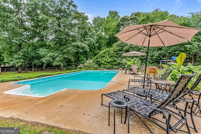 161 Mills Dr, Covington, GA 30016 - swimming pool with a patio and view of wooded area