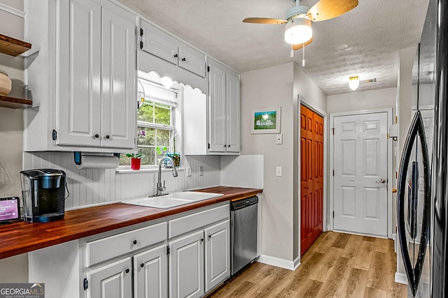 161 Mills Dr, Covington, GA 30016 - kitchen featuring wooden counters, a sink, stainless steel dishwasher, freestanding refrigerator, and a textured ceiling