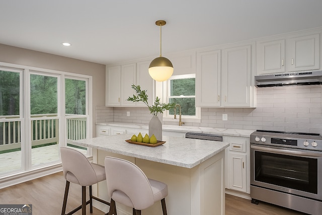 4806 Deer Chase, Powder Springs, GA 30127 - kitchen featuring electric stove, under cabinet range hood, a sink, decorative backsplash, and a kitchen breakfast bar
