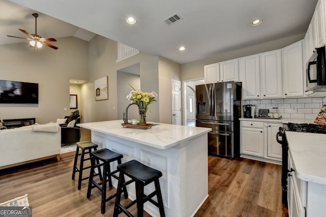 2633 Hanriva Ct, Dacula, GA 30019 - kitchen with fridge with ice dispenser, black microwave, open floor plan, white cabinets, and a ceiling fan