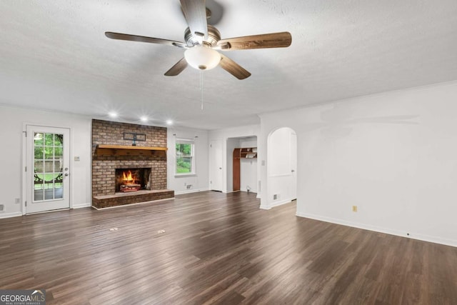 2644 Hickory Valley Dr, Snellville, GA 30078 - unfurnished living room featuring a ceiling fan, plenty of natural light, arched walkways, wood finished floors, and a textured ceiling