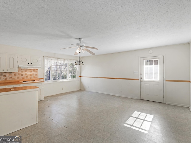 1727 Briarcliff Rd, Milledgeville, GA 31061 - kitchen with under cabinet range hood, healthy amount of natural light, white cabinets, a ceiling fan, and a textured ceiling