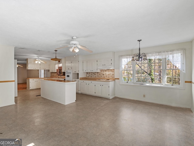 1727 Briarcliff Rd, Milledgeville, GA 31061 - kitchen with white appliances, under cabinet range hood, a kitchen island, white cabinets, and ceiling fan