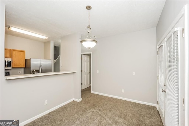 6073 Camden Forrest Dr, Riverdale, GA 30296 - kitchen with stainless steel appliances, carpet, baseboards, hanging light fixtures, and brown cabinets