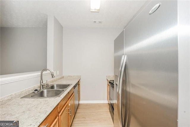 6073 Camden Forrest Dr, Riverdale, GA 30296 - kitchen with stainless steel appliances, light wood-style floors, brown cabinetry, and a textured ceiling