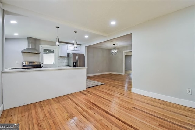 4309 Gilbert Pl, Forest Park, GA 30297 - kitchen with appliances with stainless steel finishes, wall chimney range hood, light wood finished floors, baseboards, and a peninsula