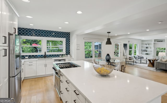 1168 Mclynn Ave NE, Atlanta, GA 30306 - kitchen with stainless steel appliances, a sink, open floor plan, light wood-style flooring, and white cabinets